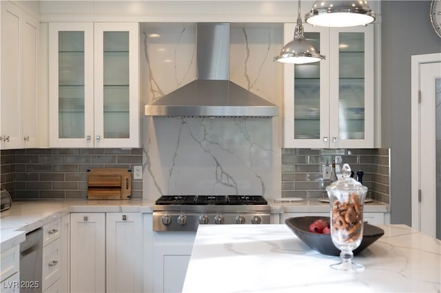 kitchen with light stone countertops, wall chimney exhaust hood, glass insert cabinets, and white cabinets