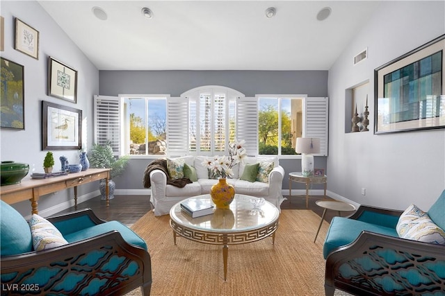 sitting room with visible vents, vaulted ceiling, baseboards, and wood finished floors