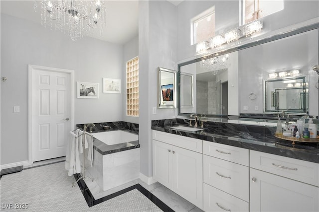 full bath with a chandelier, a garden tub, vanity, and baseboards