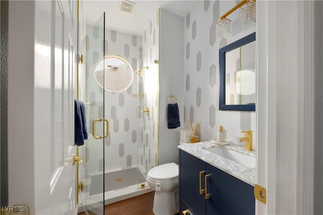 bathroom with visible vents, toilet, a shower stall, vanity, and wood finished floors