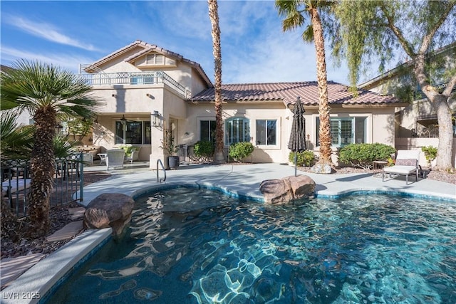 rear view of property with a patio area, an outdoor pool, a balcony, and stucco siding