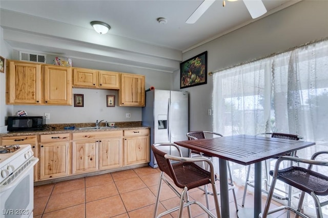 kitchen with black microwave, a sink, white gas range oven, stainless steel fridge with ice dispenser, and dark stone counters