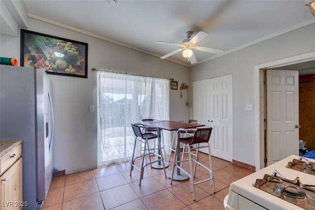 dining area with light tile patterned floors, a ceiling fan, and crown molding