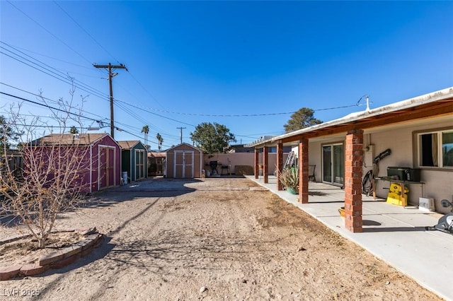 view of yard with a patio area, an outdoor structure, a storage shed, and fence