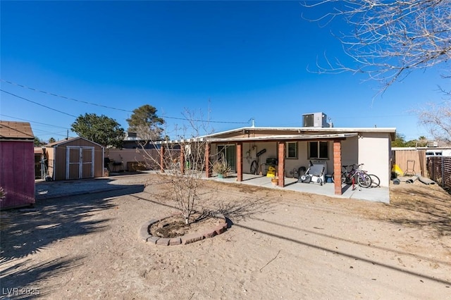 back of property with a patio area, an outdoor structure, a fenced backyard, and a shed