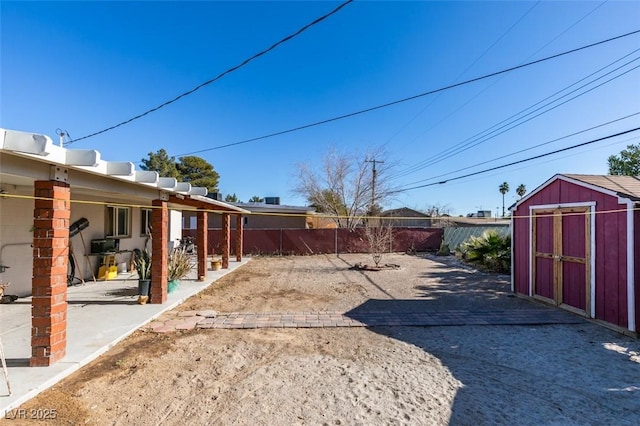 view of yard with a fenced backyard, a storage unit, a patio, and an outbuilding