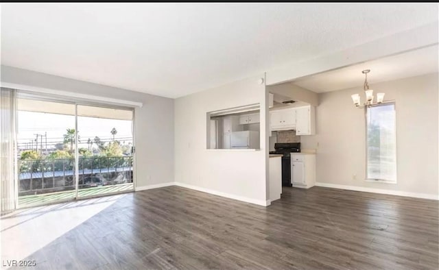 unfurnished living room featuring a chandelier, dark wood-style flooring, and baseboards