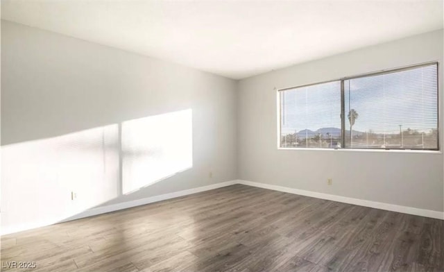 unfurnished room with dark wood finished floors and baseboards