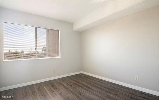 empty room with baseboards and dark wood-type flooring