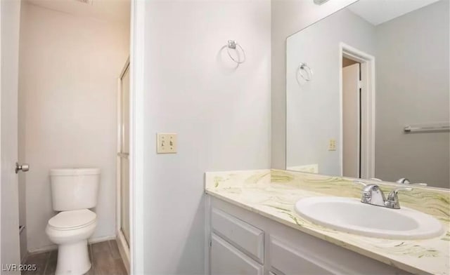 full bathroom featuring toilet, a shower with door, and vanity