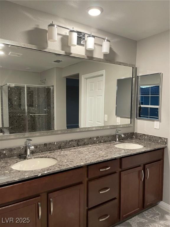 bathroom featuring a shower stall, a sink, and double vanity