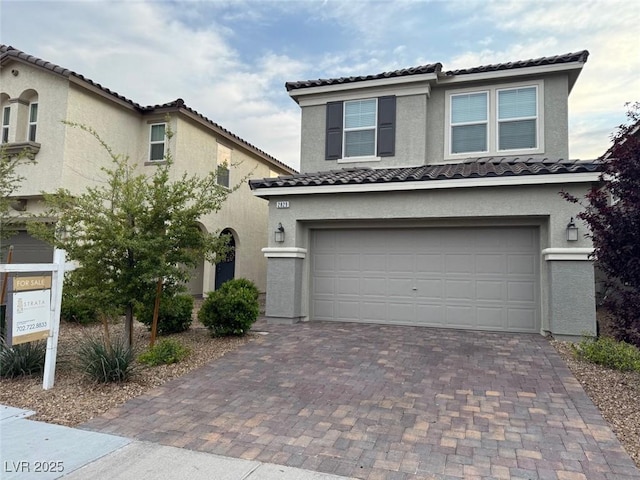 view of front facade featuring stucco siding, an attached garage, decorative driveway, and a tiled roof