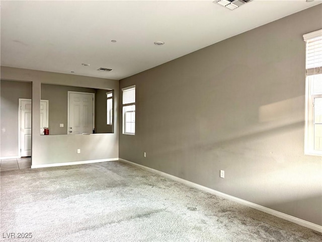 carpeted empty room featuring baseboards and visible vents