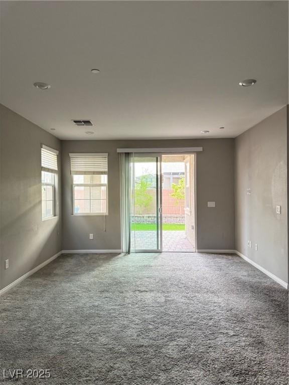 carpeted empty room featuring visible vents and baseboards