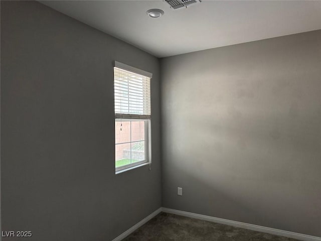 spare room featuring visible vents, plenty of natural light, baseboards, and dark carpet