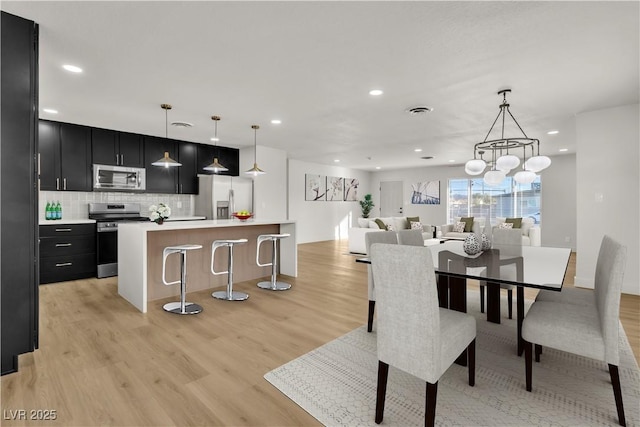 dining room featuring light wood finished floors, visible vents, and recessed lighting