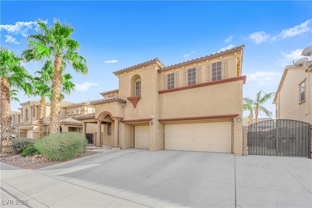 mediterranean / spanish-style house with an attached garage, driveway, a gate, and stucco siding