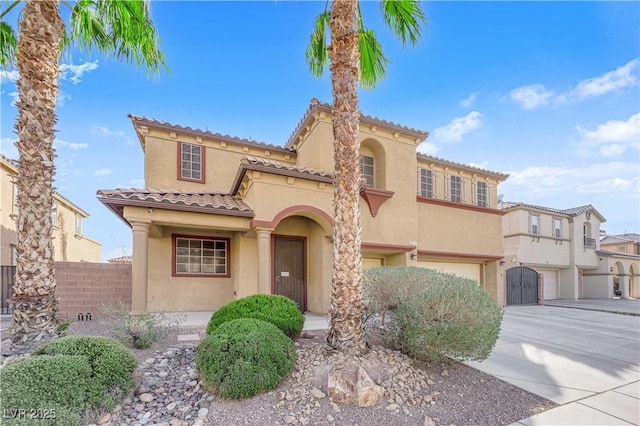 mediterranean / spanish home with a garage, fence, concrete driveway, and stucco siding