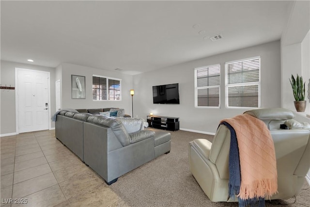 living area featuring light tile patterned floors, plenty of natural light, visible vents, and baseboards