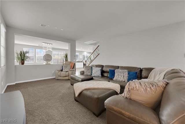 carpeted living area with baseboards, visible vents, and stairway