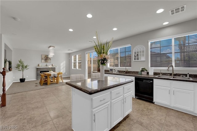 kitchen with visible vents, white cabinets, a kitchen island, a sink, and dishwasher