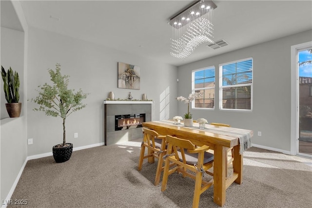 dining area with carpet floors, visible vents, a glass covered fireplace, a chandelier, and baseboards