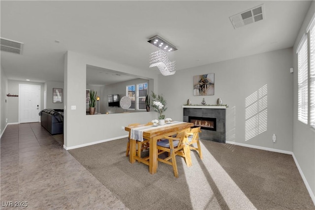 dining area featuring baseboards, a tile fireplace, visible vents, and a notable chandelier