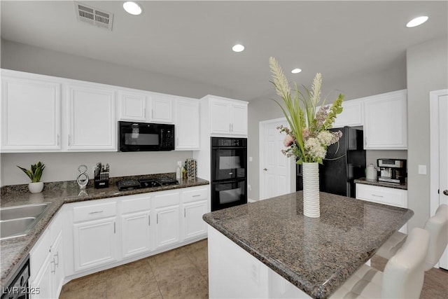 kitchen featuring visible vents, a center island, black appliances, white cabinetry, and recessed lighting