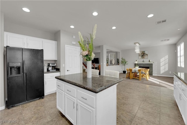 kitchen featuring visible vents, black fridge with ice dispenser, open floor plan, white cabinetry, and a kitchen island