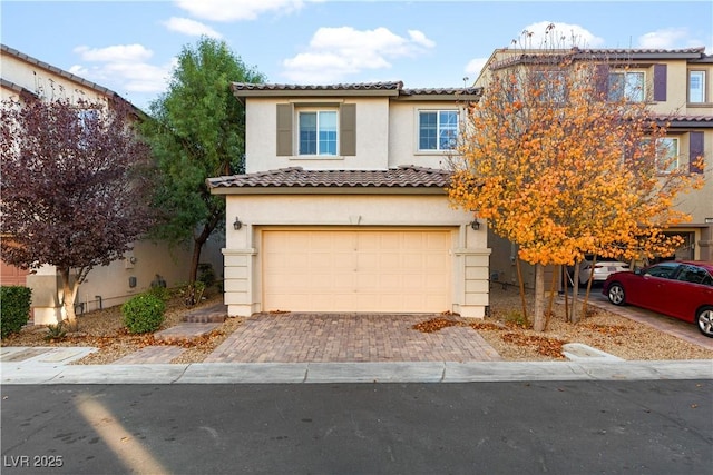 view of front of house with decorative driveway, a tile roof, an attached garage, and stucco siding