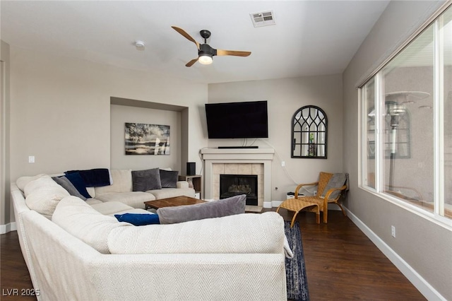 living room with baseboards, visible vents, dark wood finished floors, ceiling fan, and a fireplace