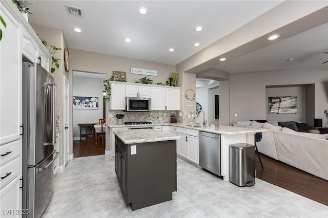 kitchen featuring open floor plan, a peninsula, appliances with stainless steel finishes, and a center island