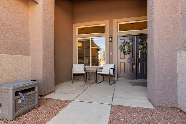 view of exterior entry featuring a patio and stucco siding