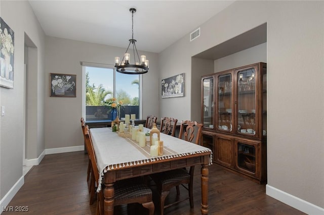 dining room featuring an inviting chandelier, visible vents, baseboards, and dark wood finished floors