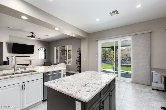 kitchen with open floor plan, white cabinets, a kitchen island, a sink, and dishwasher