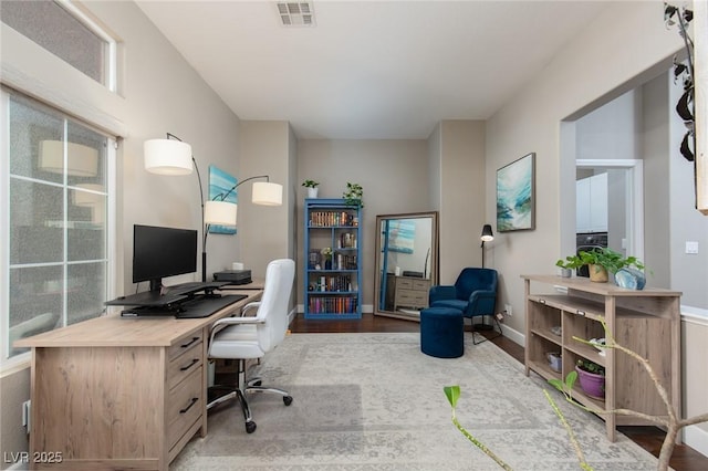 office area with baseboards, visible vents, and wood finished floors