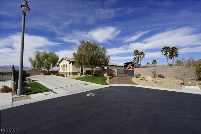 exterior space with street lights, driveway, and a gate