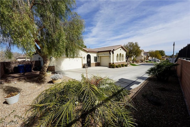 mediterranean / spanish-style house with fence, a tiled roof, concrete driveway, stucco siding, and an attached garage