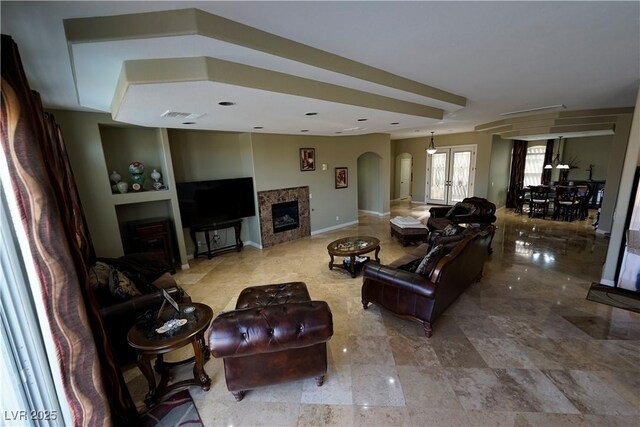 living area featuring baseboards, arched walkways, visible vents, and a fireplace