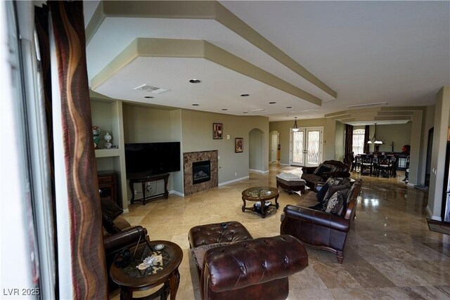 living room featuring visible vents, arched walkways, baseboards, and a glass covered fireplace