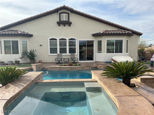 rear view of property featuring an outdoor pool, stucco siding, an in ground hot tub, and a tile roof