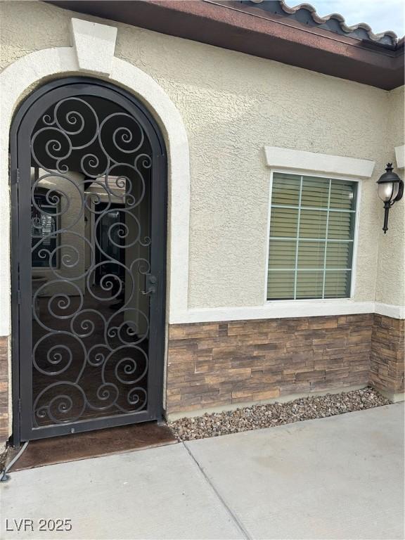 doorway to property featuring stone siding and stucco siding