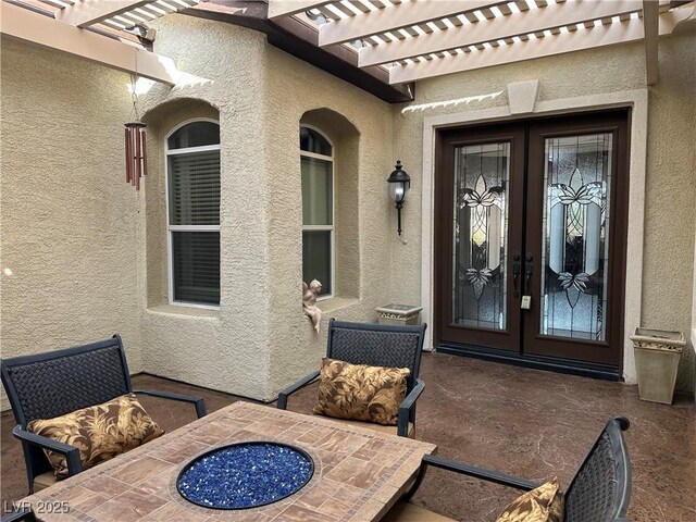 view of exterior entry featuring french doors, a pergola, and stucco siding