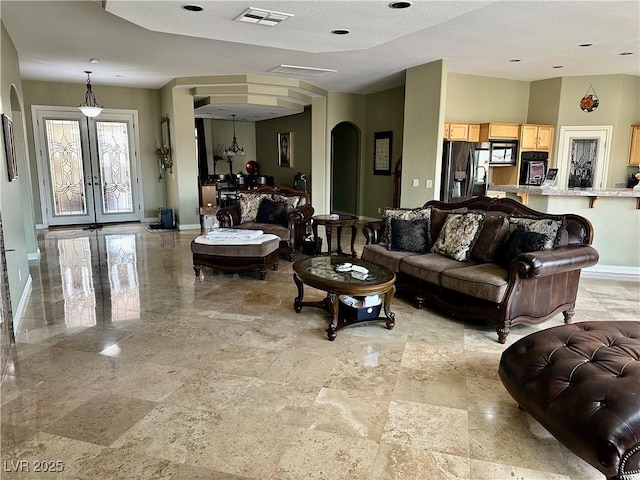 living room featuring arched walkways, visible vents, french doors, and baseboards