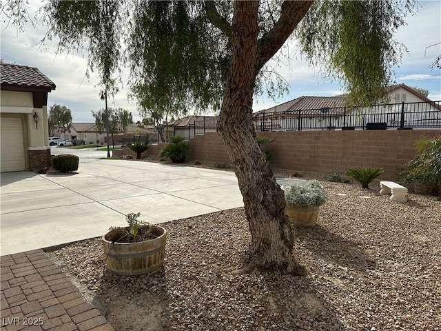 view of patio featuring a residential view, concrete driveway, and fence