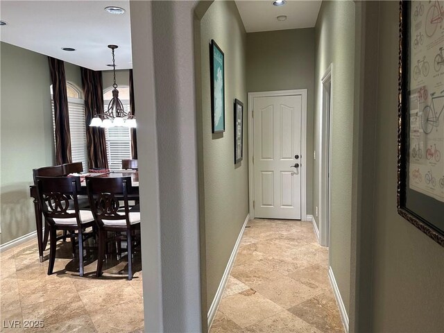 hallway featuring stone finish floor and baseboards