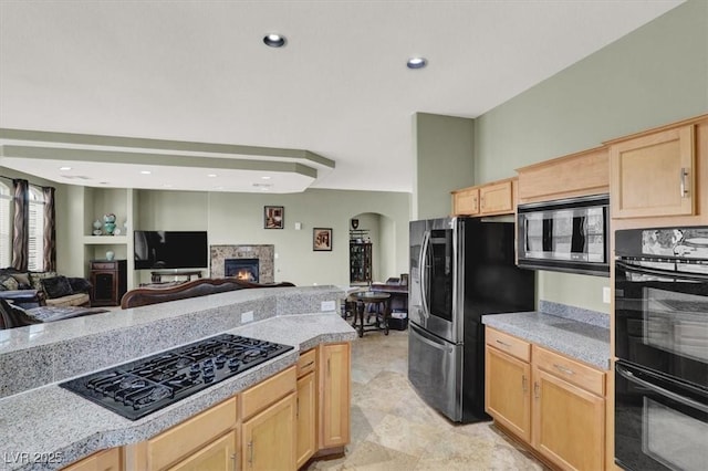 kitchen with arched walkways, light brown cabinetry, black appliances, and open floor plan