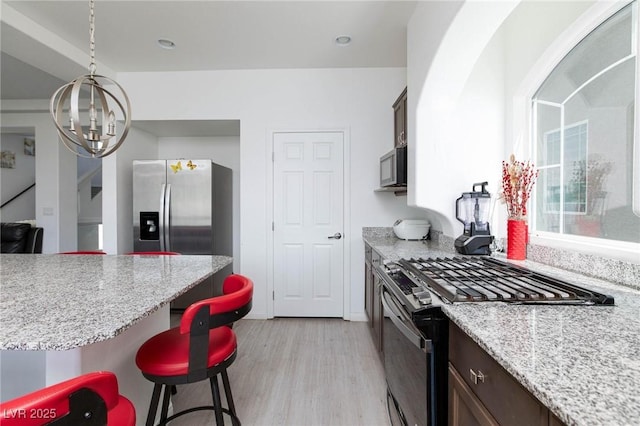 kitchen with stainless steel appliances, a breakfast bar, light wood-type flooring, and dark brown cabinets