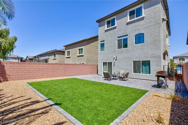 rear view of property with a yard, a fenced backyard, a patio, and stucco siding