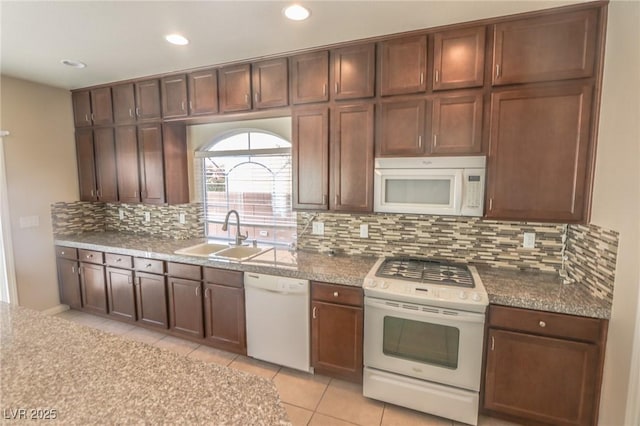 kitchen featuring white appliances, tasteful backsplash, light tile patterned floors, a sink, and recessed lighting